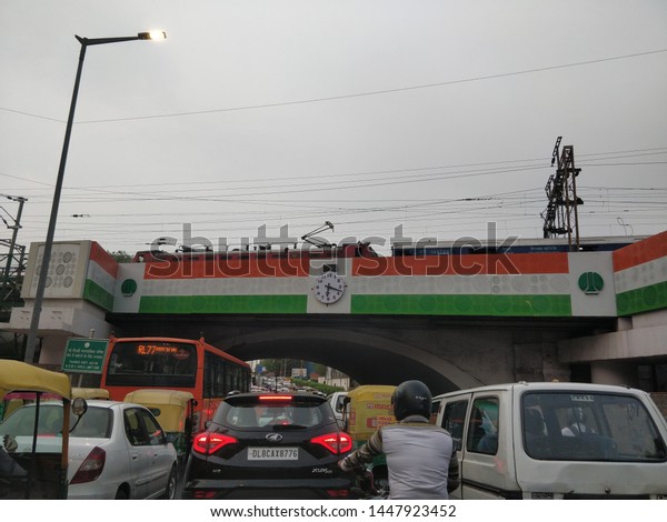 delhi/india- 07 09 19: cars and traffic under minto\
road bridge with train crossing. heavy traffic area. indian flag\
bridge. cannought\
place