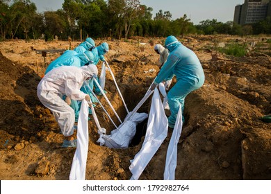 Delhi/India June-16 , 2020 : Relatives dressed in PPE suits carry a covered body of a victim who died from covid-19 disease buried at a graveyard as designated spot for Dead body