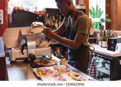 deli counter worker - cook using slicer - man preparing cold dishes and appetizers - Powered by Shutterstock