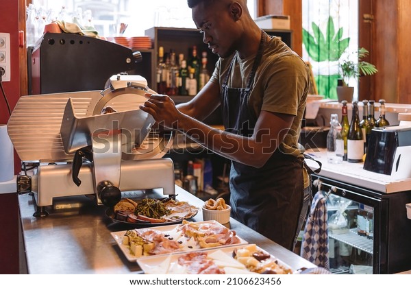 deli counter worker - cook using slicer - man\
preparing cold dishes and\
appetizers