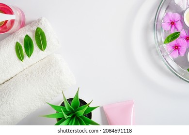 Delicate background, intimate hygiene gel, white towels and a container with pink flowers for aromatherapy. Copy space.