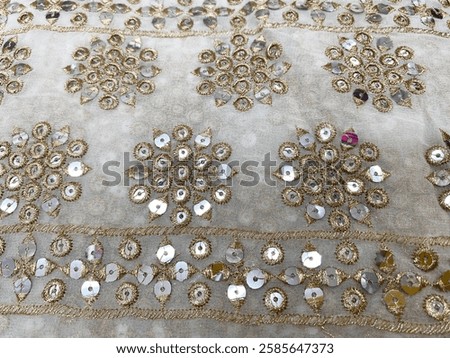A delicate border of round geometric sequin flowers adorns the soft white georgette fabric, shimmering gracefully with every movement. 