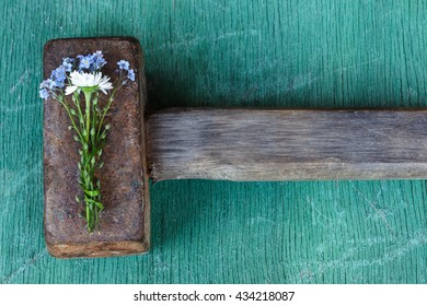 Delicate bouquet of flowers covers the heavy rough hammer. Stop the violence through love and tenderness. - Shutterstock ID 434218087