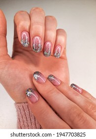 Delicate camouflage coating and silver design  Hands in sweater and pink gel polish   sequins  Stylish   shiny nail polish coating 