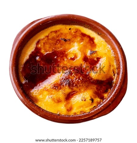 Delicate crema catalana with crisp caramel crust in clay bowl. Traditional Spanish custard dessert. Isolated over white background
