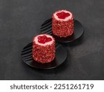 Delicate dessert without baking. Two Strawberry Mousse cakes of cylindrical shape, sprinkled with small pieces of freeze-dried strawberries and decorated with cute red jelly hearts. Valentine
