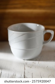 A delicate gray cup with subtle lines sits gracefully on a weathered table, basking in soft natural light.