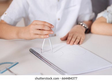 Delicate hands of a boy using a compass