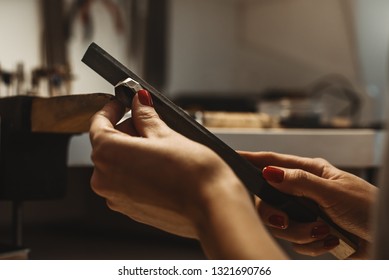 Delicate jewelry work. Close up of a female jeweler's hands working and shaping an unfinished ring with a tool at workbench in workshop - Powered by Shutterstock