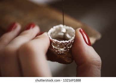 Delicate jewelry work. Close up of a female jeweler's hand working on a ring resizing at her workbench.