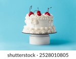 Delicate lambeth style birthday cake with white cream cheese frosting decorated with cocktail cherries on the blue background