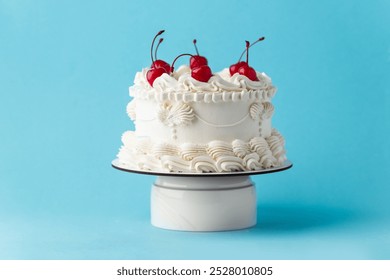 Delicate lambeth style birthday cake with white cream cheese frosting decorated with cocktail cherries on the blue background