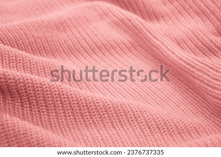 Delicate light pink coral knitted sweater. Folded surface as an abstract background with texture.