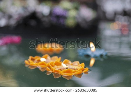 Delicate lotus candles gently float calm water, their warm light creating peaceful, spiritual atmosphere. Each burning flame adds tranquil glow to this serene evening ceremony, perfect