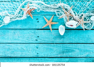 Delicate nautical border with fishing net, sea shells and starfish on a background of colourful turquoise blue painted wooden boards with copyspace for your text - Shutterstock ID 181135754
