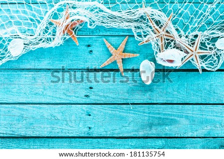 Delicate nautical border with fishing net, sea shells and starfish on a background of colourful turquoise blue painted wooden boards with copyspace for your text