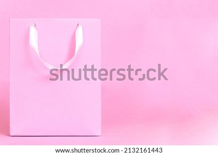 A delicate pink package on a pink background is the concept of discounts and sales. place for text, copyspace Paper shopping bag on pink background. Shopping sale delivery concept
