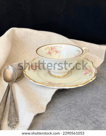 Delicate retro cup and sauce with two old spoons by the side. 