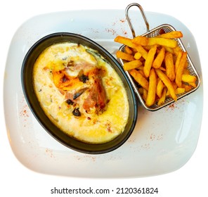 Delicate Savoyard chicken escalope baked with bacon and zucchini in creamy sauce with dry white wine and emmental cheese, served with crispy fries. Isolated over white background
