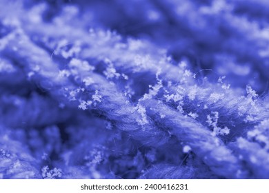Delicate white snowflakes gently descend onto woolen knitted background, macro detail, winter romance and meteorological phenomena, seasonal changes