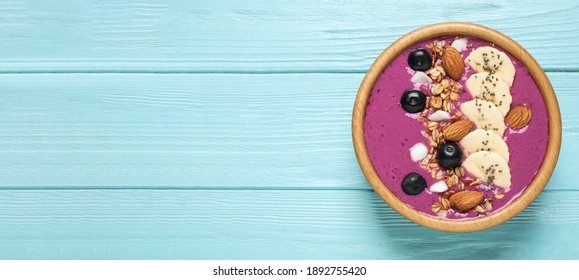 Delicious Acai Smoothie With Granola And Almonds In Dessert Bowl On Light Blue Wooden Table, Top View. Space For Text