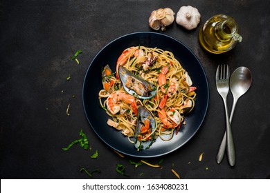 Delicious Appetizing Fresh Spaghetti With Spicy Mixed Seafood On Dark Background.Space For Text. Overhead. Dark Rustic Wooden Table. Dinner With Pasta