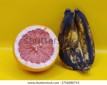 Delicious appetizing fruit composition of half a grapefruit and several bananas on a yellow background, macro photography