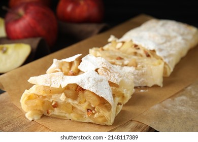 Delicious apple strudel with almonds and powdered sugar on wooden board, closeup