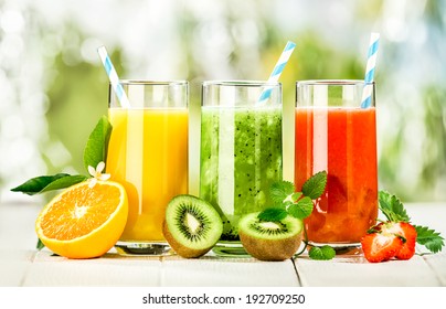 Delicious array of fresh fruit juices served in tall glasses made from liquidised orange, kiwifruit with peppermint, and strawberries for healthy summer treats rich in vitamins