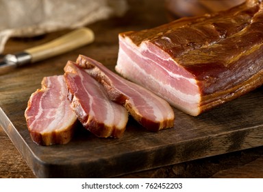 Delicious artisanal whole smoked slab bacon on a cutting block.