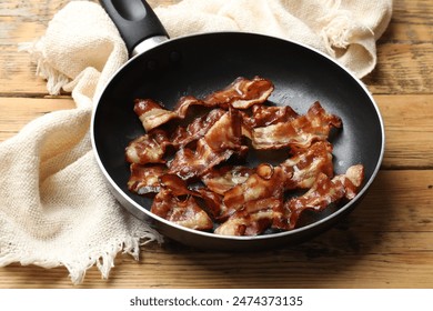 Delicious bacon slices in frying pan on wooden table