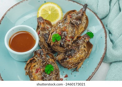 Delicious baked artichoke with parmesan cheese and sauce. Olive oil, garlic, parsley and lemon. Light stone concrete background, ready to eat vegan food, close up - Powered by Shutterstock