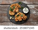 Delicious baked cauliflower steaks with sauce on wooden table, top view