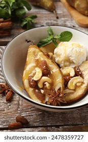 Delicious baked pears with nuts, ice cream, anise stars and honey in bowl on wooden rustic table, closeup