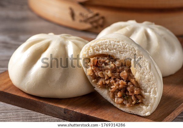 Delicious baozi, Chinese steamed meat bun is\
ready to eat on serving plate and steamer, close up, copy space\
product design\
concept.
