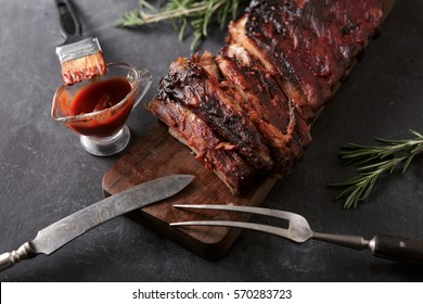 Delicious Barbecued Ribs Seasoned With A Spicy Basting Sauce And Served With Chopped Fresh Vegetables On An Old Rustic Wooden Chopping Board In A Country Kitchen