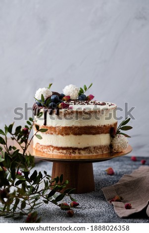 Delicious and beautiful handmade cake. Confectionery for the holiday. Dessert decorated with fresh berries, green leaves and sweets.