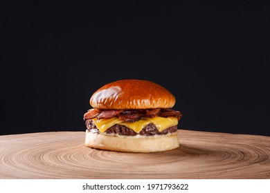 Delicious beef burger with bacon and cheddar cheese on wooden table on dark background. Copy space - Powered by Shutterstock