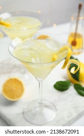 Delicious bee's knees cocktail with ice and lemon twist on white table