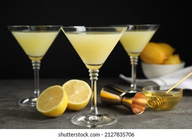 Delicious bee's knees cocktails and ingredients on grey table against black background