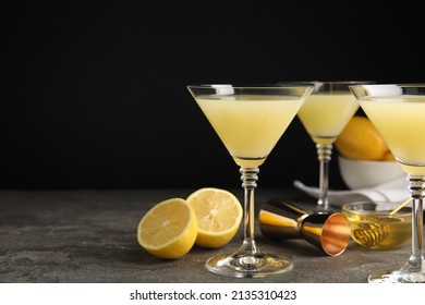 Delicious bee's knees cocktails and ingredients on grey table against black background, space for text