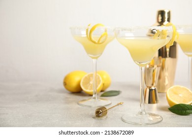 Delicious bee's knees cocktails and ingredients on light grey table, space for text