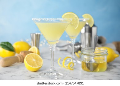 Delicious bee's knees cocktails and ingredients on white marble table against light blue background