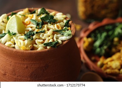 Delicious Bengali street food and evening snack, jhalmuri, in a earthen pot is placed on a wooden surface with its ingredients being arranged in a earthen plate. Bengali food of emotion and love.