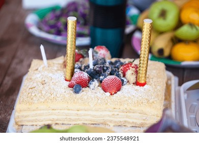 Delicious berry cake with two candles, close up view