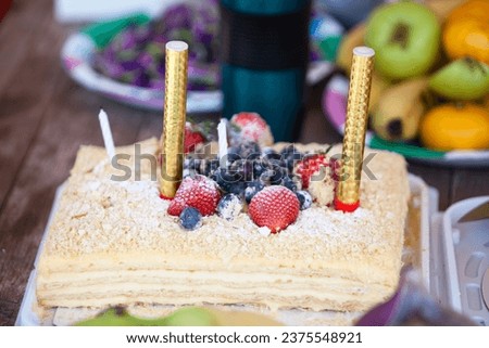 Delicious berry cake with two candles, close up view