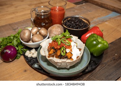 A Delicious Black Bean Burrito Bowl And The  Ingredients Used To Make It On A Wooden Kitchen Work Top