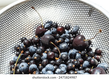 Delicious black berries , cherries, blueberries in metal basket rinsed with water in kitchen sink . Summer organic food. Berry harvesting season - Powered by Shutterstock