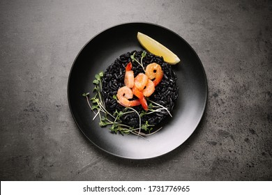 Delicious Black Risotto With Shrimps And Lemon On Grey Table, Top View. Food Photography  