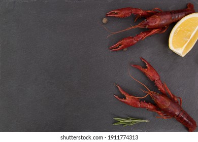 Delicious boiled crayfish close-up on a stone plate with pepper, lemon and parsley.